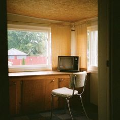 a chair sitting in front of a window with a microwave on it's side