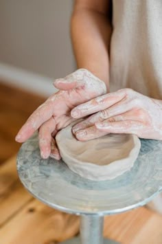 a person with their hands on a pottery bowl that is sitting on a table top