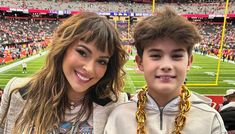 a young man and woman standing next to each other at a football game