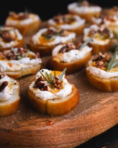 small appetizers are arranged on a wooden platter with rosemary sprigs