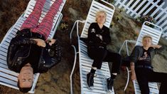 three people laying on lawn chairs in the sand