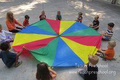 a group of children sitting around a colorful umbrella