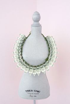 a white mannequin with a green necklace on it