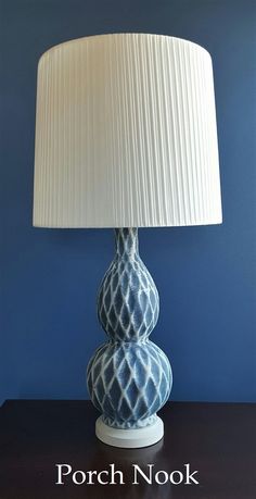 a blue and white lamp sitting on top of a table next to a blue wall