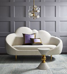 a white couch sitting on top of a blue rug next to a table with two pillows