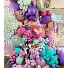 a bunch of balloons that are on top of some grass with flowers and butterflies around them