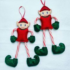 two christmas ornaments made to look like elfs with candy canes in their hands