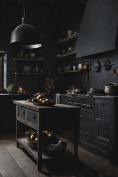 an old fashioned kitchen with black walls and wooden flooring is lit by pendant lights hanging from the ceiling