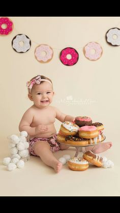 a baby sitting on the floor with doughnuts and marshmallows in front of her