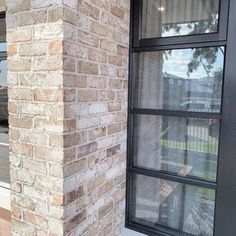 a cat sitting on the ledge of a brick building next to a window with glass panes