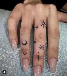 a woman's hand with stars and moon tattoos on it