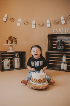 a baby sitting on the floor with a cake in front of him