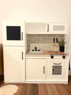 a small kitchen with white cabinets and wood flooring, along with a rug on the floor