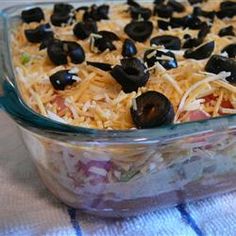 a casserole dish with black olives and shredded cheese in the bottom layer