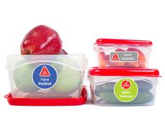 three plastic containers with apples and vegetables in them