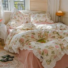 a bed with pink and white flowers on it in a bedroom next to a window