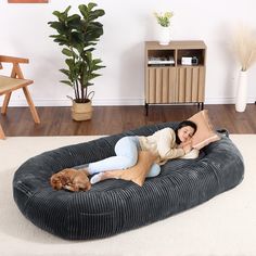 a woman laying on top of a dog bed in the middle of a living room