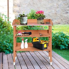 a potted plant sitting on top of a wooden shelf next to gardening tools and flowers