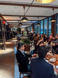 several people sitting at tables in a restaurant with large windows and panoramic view