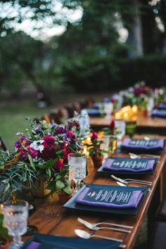 a long table with place settings and flowers on it