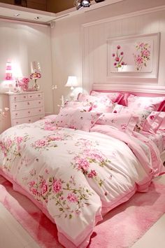 a bed with pink flowers on it in a white room next to a dresser and mirror