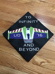 a graduation cap with the words to infinity and beyond on it sitting on top of a wooden floor