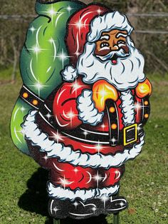 a santa clause painted on the side of a mailbox in a park with trees and grass