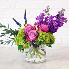 a glass vase filled with purple and green flowers