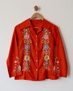 60s 70s Vintage Floral Embroidered Button Up Shirt Size M Hippie 60s 70s era, vintage button up shirt, orange fabric with detailed floral embroidery on chest and sleeves. Item is sold as is. Shirt has some unhemming on the body that may need repairing but is functional and wearable. Measurements Chest: 16.75 in Length: 23.5 in Sleeve Length: 21.1 in Open to offers. Feel free to ask any further questions. All items listed are cleaned and cared for so when you get it out the package you can immedi Long Sleeve Orange Top With Floral Embroidery, Orange Long Sleeve Blouse With Floral Embroidery, Orange Floral Embroidered Long Sleeve Top, Spring Embroidered Orange Blouse, Orange Floral Embroidered Cotton Top, Red Embroidered Shirt For Spring, Orange Cotton Top With Floral Embroidery, Retro Long Sleeve Top With Floral Embroidery, Vintage Orange Long Sleeve Shirt