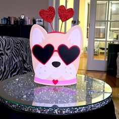 a dog with heart shaped sunglasses on top of a table in a living room area