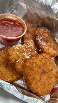 some fried food is in a basket with sauce on the side and ketchup