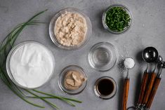 the ingredients to make an appetizer laid out on a gray surface with spoons and measuring cups