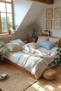 an unmade bed sitting in a bedroom next to a window and potted plant