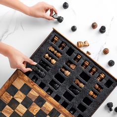 two hands are playing chess on a marble table with black and white checkered pieces