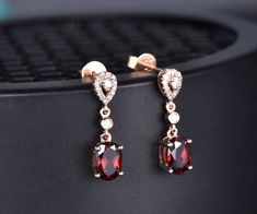 two pairs of red and white cubicge earrings on top of a black piece of metal