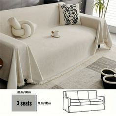 a white couch with three pillows and a throw pillow on the back, next to a coffee table