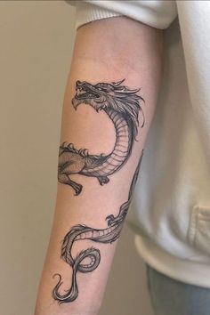 a woman's arm with a dragon tattoo on the left side of her arm