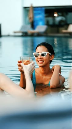 a woman in a swimming pool holding a drink