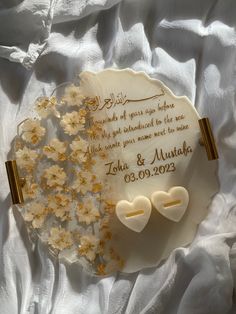 a wedding cake decorated with flowers and two heart - shaped cookies on a white plate