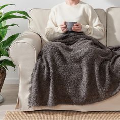 a woman sitting on a couch holding a cup