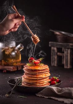 a stack of pancakes with syrup being poured on top