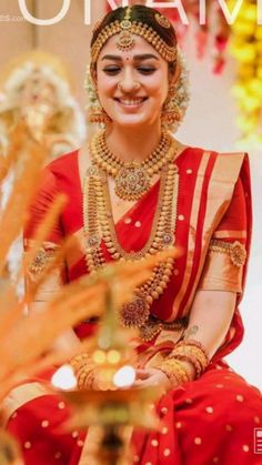 a woman in a red and gold sari smiles at the camera with her hands on her hips