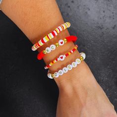 Set of 4 Kansas City Chiefs Game Day hand-beaded, stretch bracelets. Each strand is made with 6 mm clay beads with 14 K gold plated accents. Free shipping on orders $35 and over is guaranteed. Details:  🖤Handmade Item 🖤Ships from Lansing, KS  🖤Bracelet Length: M - 6.75" (Standard) 🖤Materials: Heishi Clay Disc Beads, 14K Gold Plated Beads, Letter Beads 🖤Closure: Tie 🖤Made to Order ✨ Please measure your wrist before ordering as we do not offer returns or exchanges for resizing.  ✨You may req Nfl Beaded Bracelets, Chiefs Game Day, Heishi Bracelets, Artsy Jewelry, Chiefs Game, Bracelet Inspo, Disc Bracelet, Fun Bracelet, Clay Bracelet