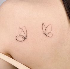 two small tattoos on the back of a woman's shoulder