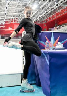 a woman in black shirt and leggings standing on blue carpet next to table