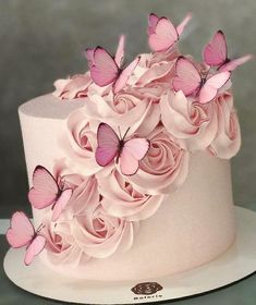 a white cake with pink flowers and butterflies on top