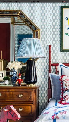 a bedroom with blue and white wallpaper, a red wooden bed frame, an antique dresser and a pink rocking horse