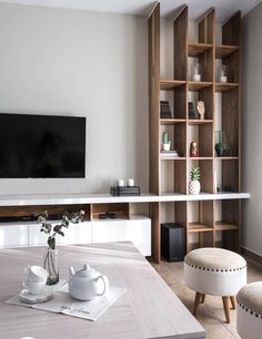 a living room filled with furniture and a flat screen tv mounted on a wall above a wooden table