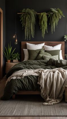 a bed covered in green blankets and pillows next to potted plants on the wall