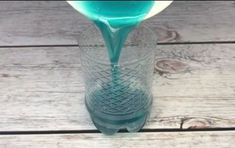 a glass vase filled with blue liquid on top of a wooden table